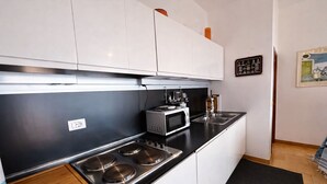 Una cocina moderna con armarios blancos, encimera negra, microondas, estufa y fregadero.