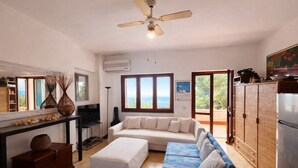 Una sala de estar con sofá, otomanas y ventilador de techo.
