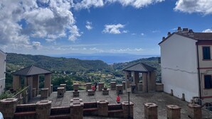 A courtyard with stone structures and a view of a valley. - La Casina Riese in the heart of Rio nell'Elba (Rio dell'Elba)