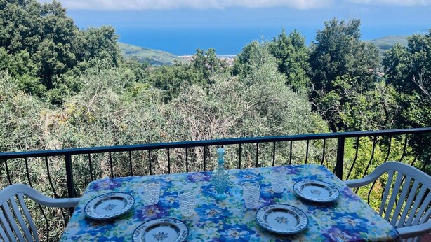 A table set outdoors with a view of the sea and hills.