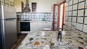 A kitchen with a refrigerator, stove, sink, and cabinets. There is a dining table with a placemat featuring food illustrations.