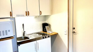 A compact kitchen with white cabinets, a stove, and a sink. - Sölvesborgs Golfklubb (Sölvesborg)