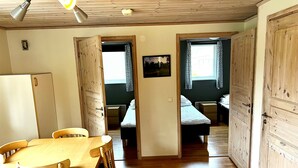 A room with a wooden dining table and chairs, a bed with a white mattress, and a wooden wardrobe. - Sölvesborgs Golfklubb (Sölvesborg)