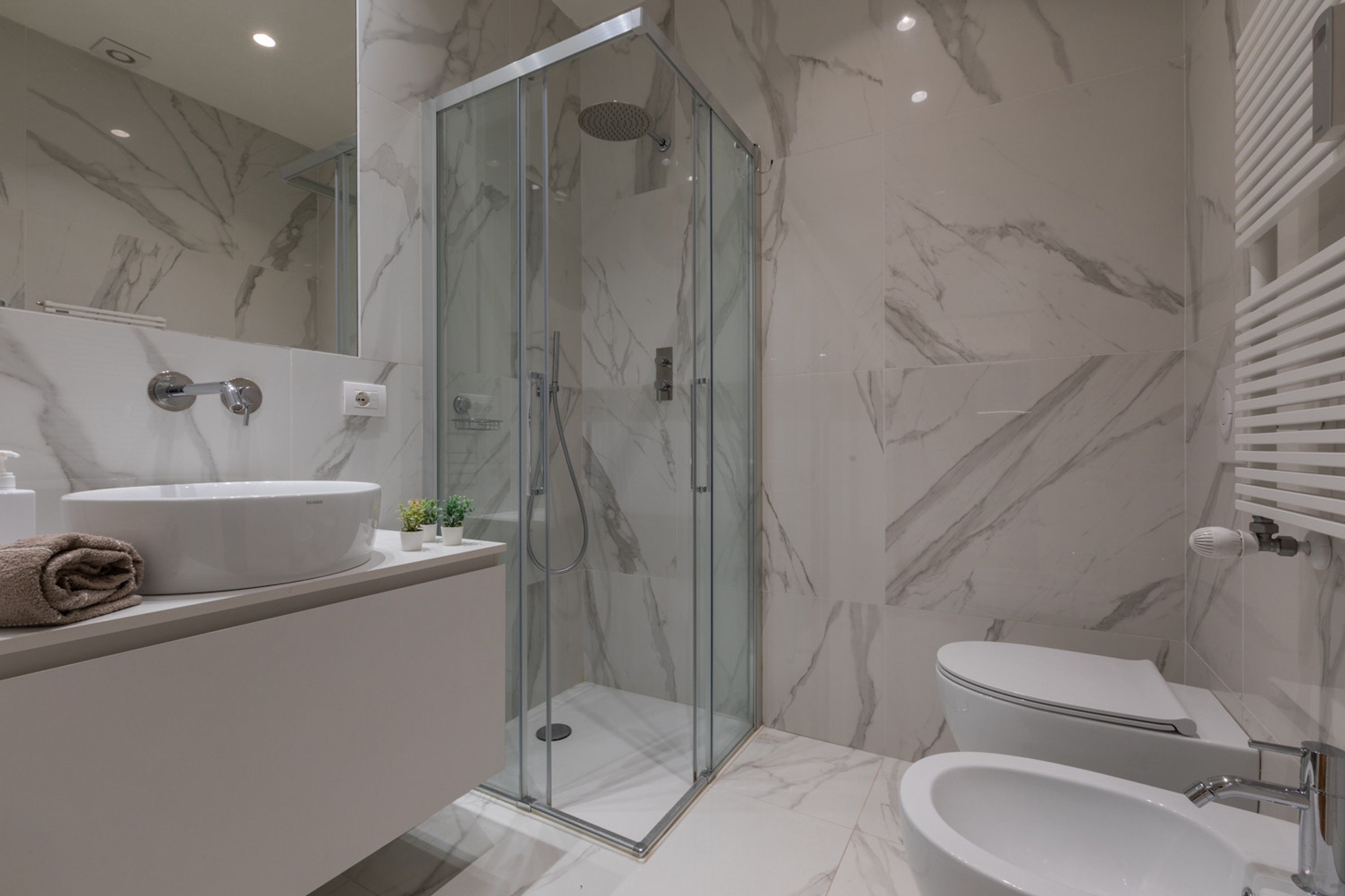 Un baño moderno con ducha de vidrio, lavamanos blanco y retrete.