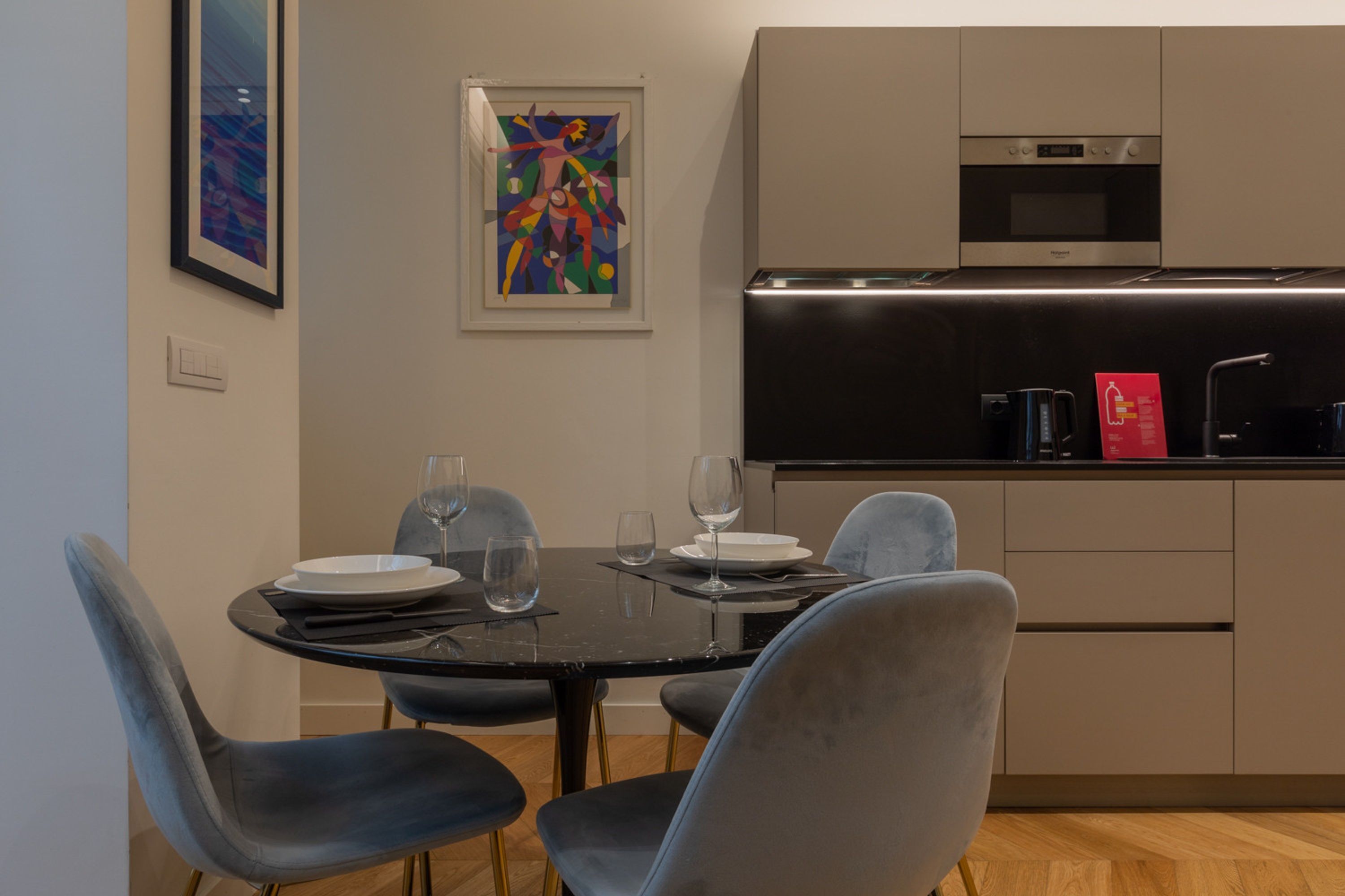 A modern kitchen with a black countertop, stainless steel appliances, and a dining area with a round table and chairs.