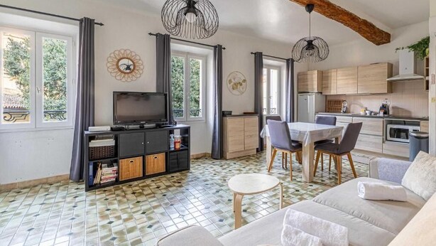 Un salon moderne avec un canapé, un téléviseur et un coin repas.