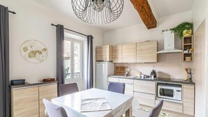 Une cuisine moderne avec des meubles de couleur bois clair, un îlot central et un coin repas comprenant une table et des chaises.
