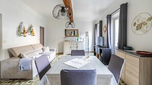Un salon moderne comprenant un canapé, une table à manger et des chaises. Il y a également un coin cuisine avec des placards et un téléviseur.