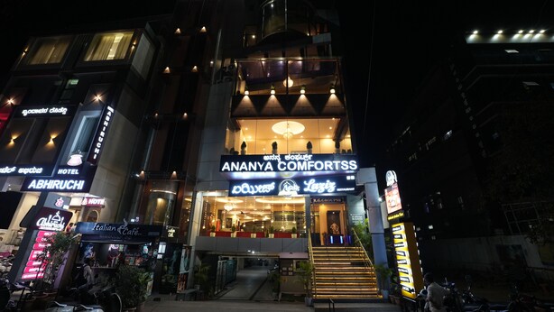 A hotel with a prominent sign for 'Ananya Comforts' and a visible staircase leading to the entrance. - Ananya Dorms (Hospet)