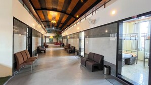 A hallway with seating areas and a bunk room visible through the glass doors. - Ananya Dorms (Hospet)