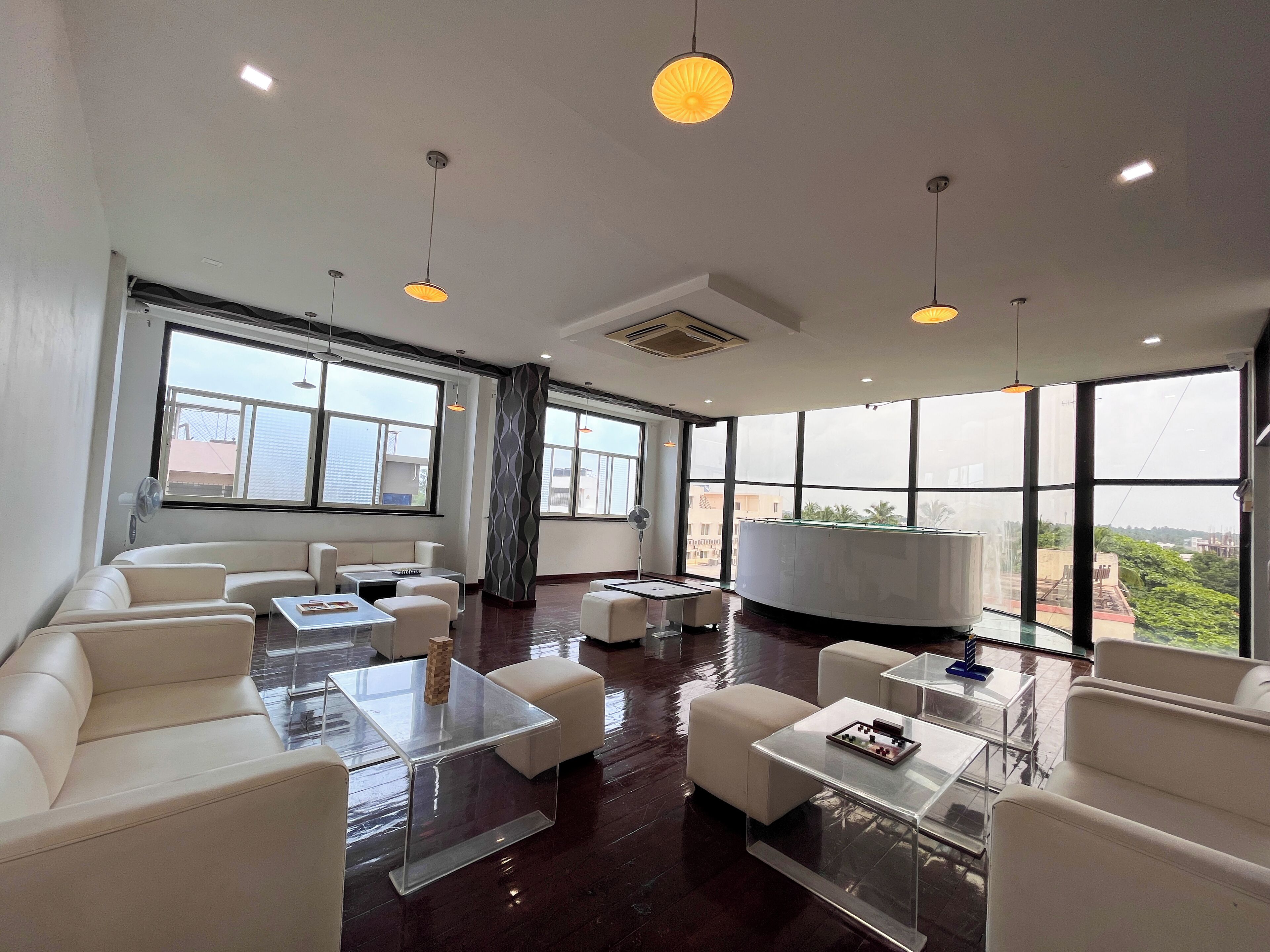 Un moderno vestíbulo de hotel con sofás de cuero blanco, mesas de centro de vidrio y grandes ventanales con vistas a la ciudad.