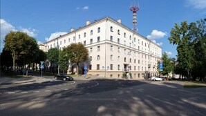 A large, multi-story building with a prominent tower, likely a government or historical building, surrounded by trees and parked cars. - Lux apartment with view on Svisloch (Minsk)