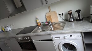 Een moderne keuken met een ingebouwde oven, een vaatwasser en een wasmachine.