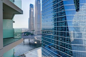 A high-rise building with a modern glass facade, a view of a river, and a bridge in the background.
