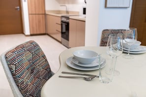 A dining area with a table set for four, including plates, bowls, glasses, and cutlery.