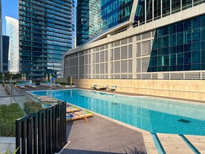 Ein modernes Gebäude mit Pool auf dem Dach, umgeben von hohen Wohnhäusern.