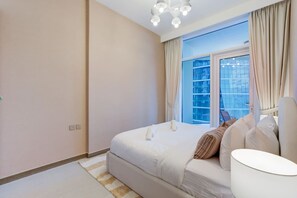 Ein modernes Schlafzimmer mit einem großen Bett, einem Nachttisch und einem Fenster mit Vorhängen.