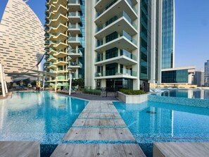 A modern hotel with a swimming pool, multiple balconies, and a contemporary architectural design. - Luxury & Elegant Apartment w Spectacular Amenities (Dubai)