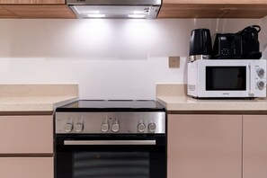 A kitchen with a Bosch range hood, a Kenwood microwave, and a stove.