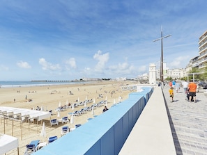 Ein Strand mit Liegestühlen und Sonnenschirmen, ein Pier in der Ferne und ein Glockenturm.