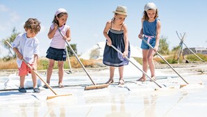 A group of children playing on a sandy beach with beach equipment.