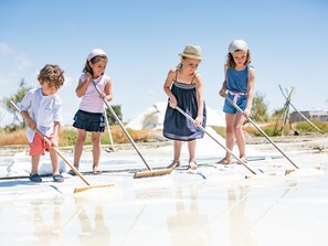 A group of children playing on a sandy beach with beach equipment.