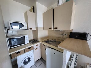 Eine kleine Küche mit Mikrowelle, Backofen, Spüle und Waschmaschine.