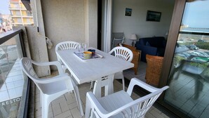 A balcony with a table and chairs, a sofa, and a view of the city.