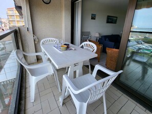 Relax on the balcony with a comfortable sofa, two chairs, and a wicker chair, offering a view of the surrounding area.