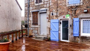 Una calle estrecha con edificios de piedra, puertas de madera y una terraza de madera.