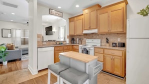 A modern kitchen with wooden cabinets, a built-in stove, and a dining area with a bench.