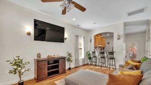 A modern living room with a gray sofa, wooden entertainment unit, and a ceiling fan.