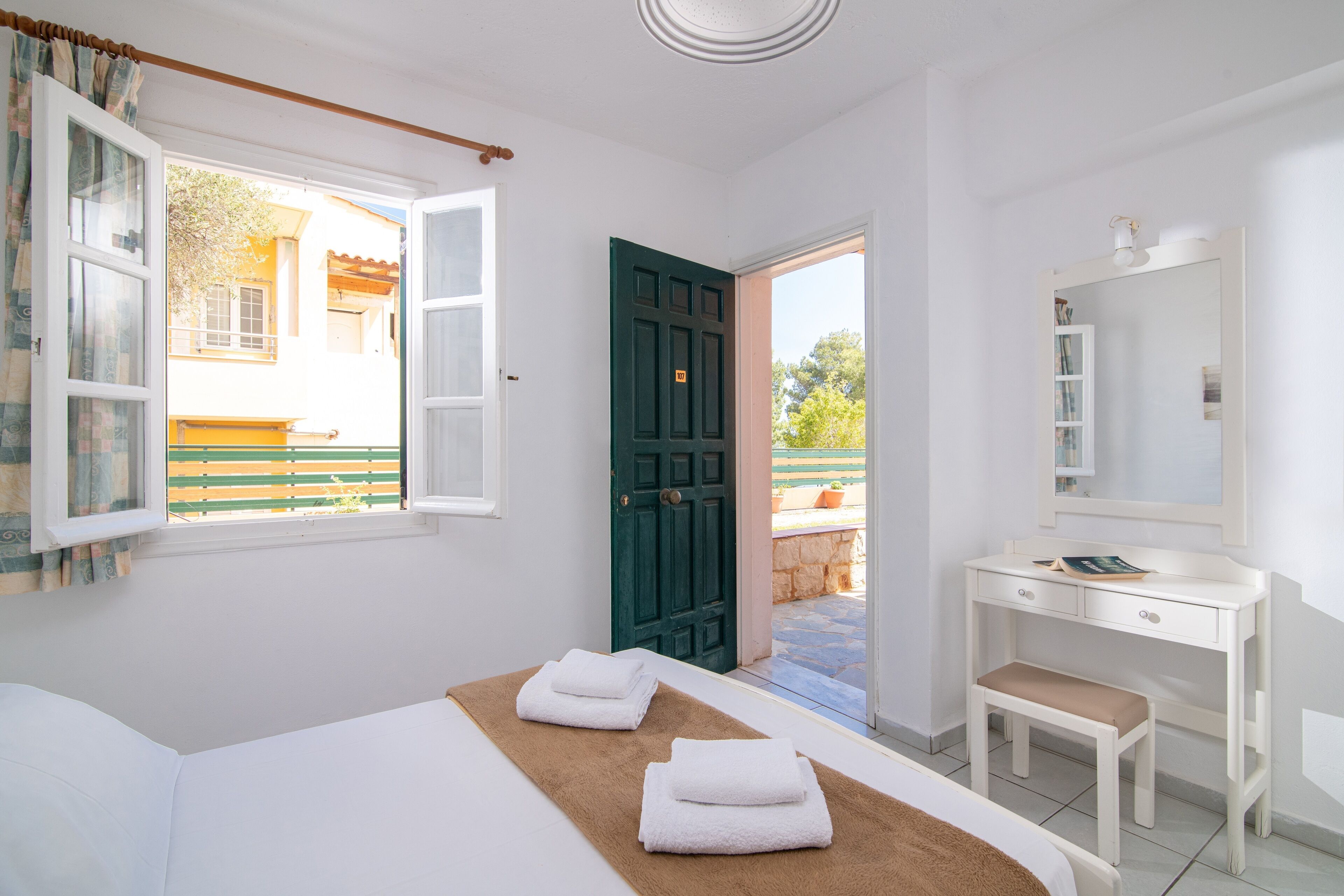 Une chambre à coucher avec un lit, un bureau, une chaise et une porte verte.