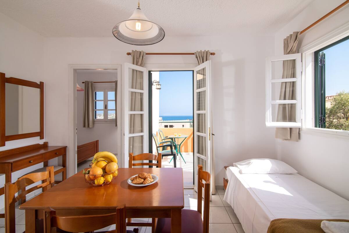 Una habitación con una mesa de comedor, sillas, una cama y vista al mar.