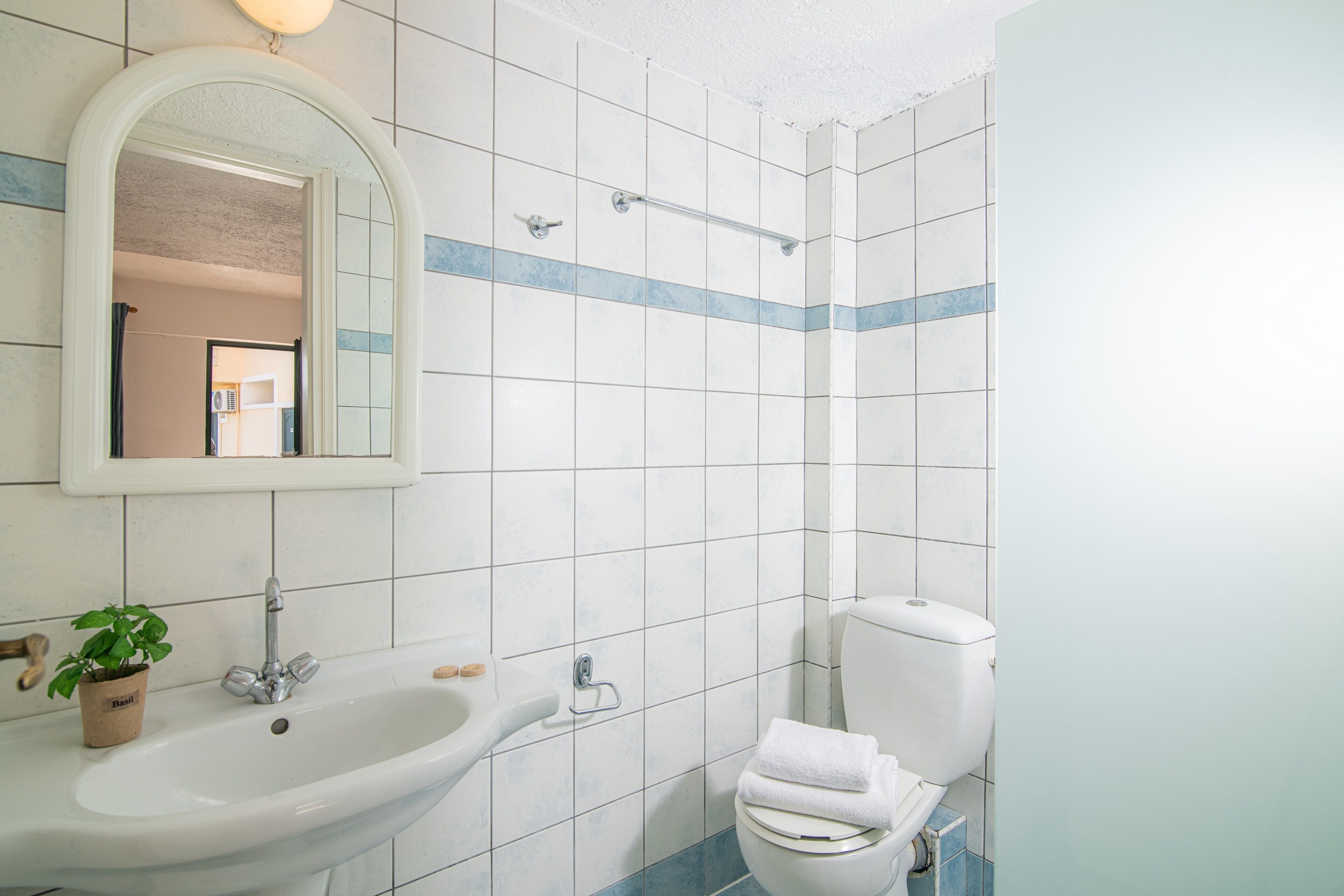 Un baño con lavamanos, espejo, inodoro y ducha.
