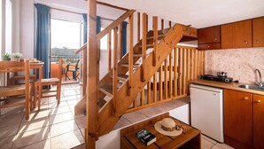 A kitchen with wooden cabinets, a sink, and a small refrigerator. There is a wooden staircase leading to an upper level. - Golden Valentin Apartments (Hersonissos)