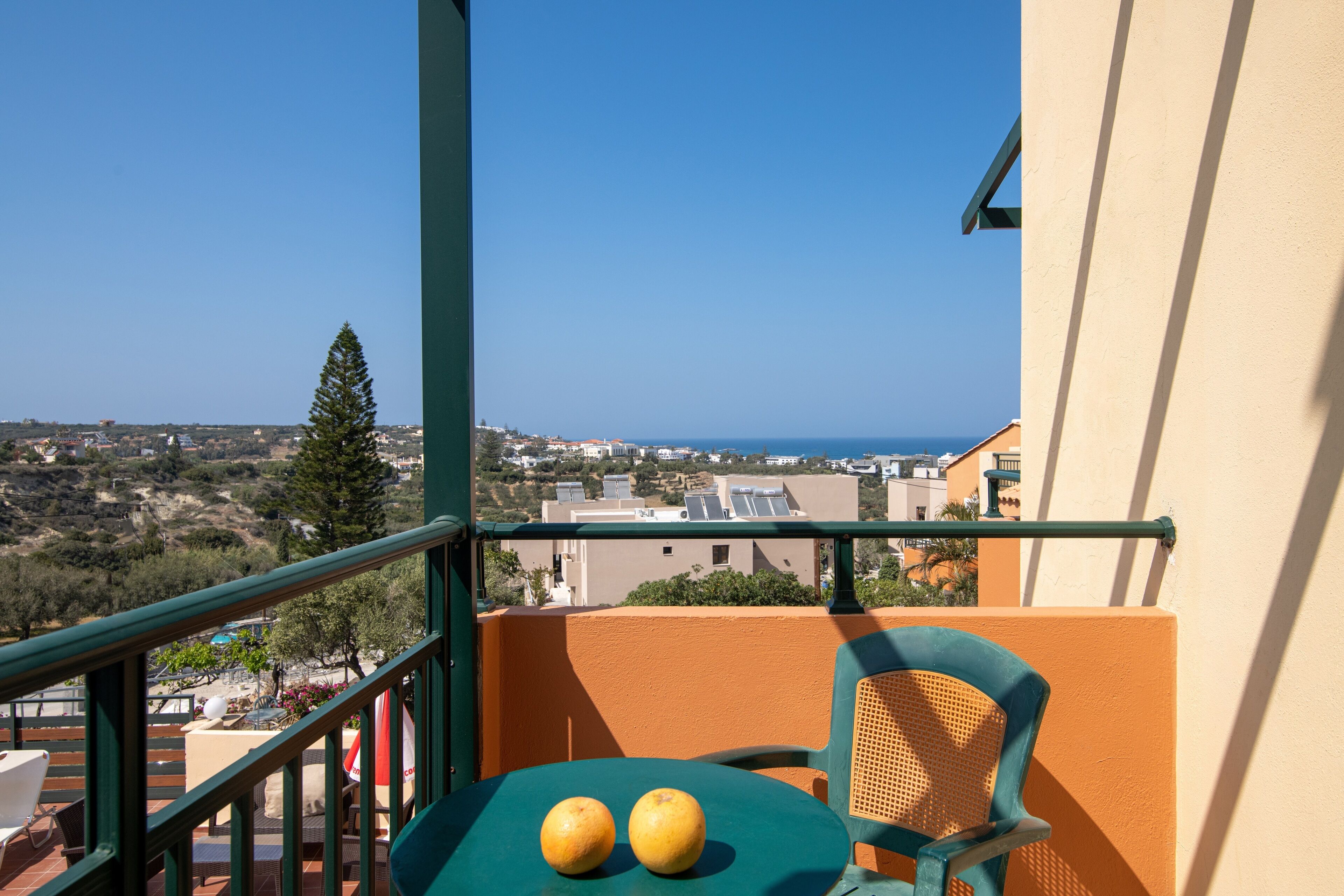 Un balcón con dos naranjas sobre una mesa, con vistas a un pueblo costero.