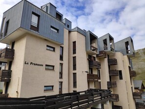 Un edificio moderno de varios pisos con fachada color beige y detalles oscuros.