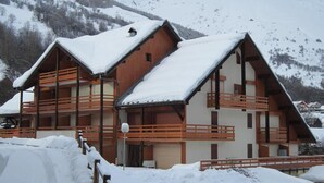 A chalet-style building with multiple balconies, surrounded by snow-covered mountains. - Charming south-facing studio, 4 pers, balcony in Valloire (Valloire)