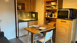 A compact kitchen with wooden cabinets, a microwave, and a sink. - Charming south-facing studio, 4 pers, balcony in Valloire (Valloire)