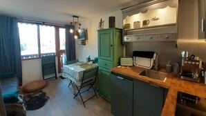 A compact kitchen with a dining area, a green cabinet, a small refrigerator, and a sink. - Renovated studio in Valfréjus, near cable car and shops (Valfréjus)