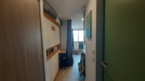 A narrow hallway with a wooden door on the left, a green door on the right, and a window at the end. - Renovated studio in Valfréjus, near cable car and shops (Valfréjus)