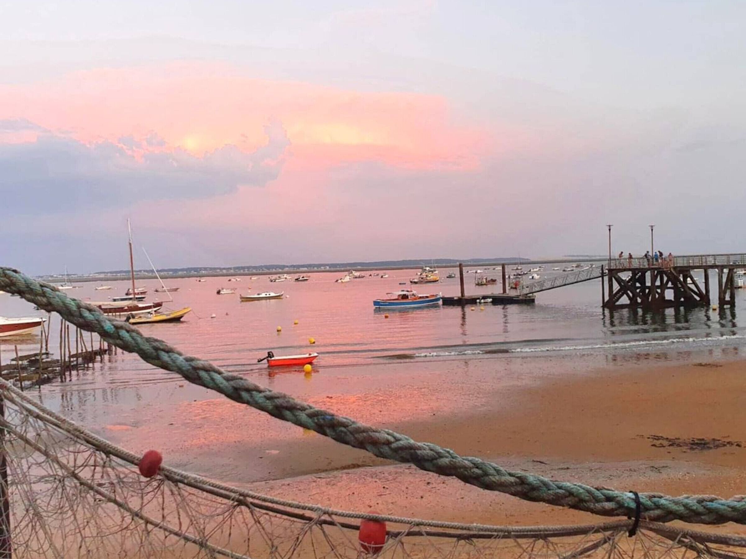 Un paysage côtier avec des bateaux, une jetée et une barrière faite de cordes.