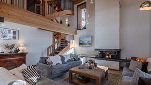 A spacious living room with a high wooden ceiling, a fireplace, and a cozy seating area. - Modern chalet in Morzine, 12 pers, 5 br, near center (Morzine)