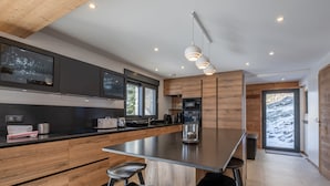 A modern kitchen with a central island, wooden cabinets, and bar stools. - Modern chalet in Morzine, 12 pers, 5 br, near center (Morzine)