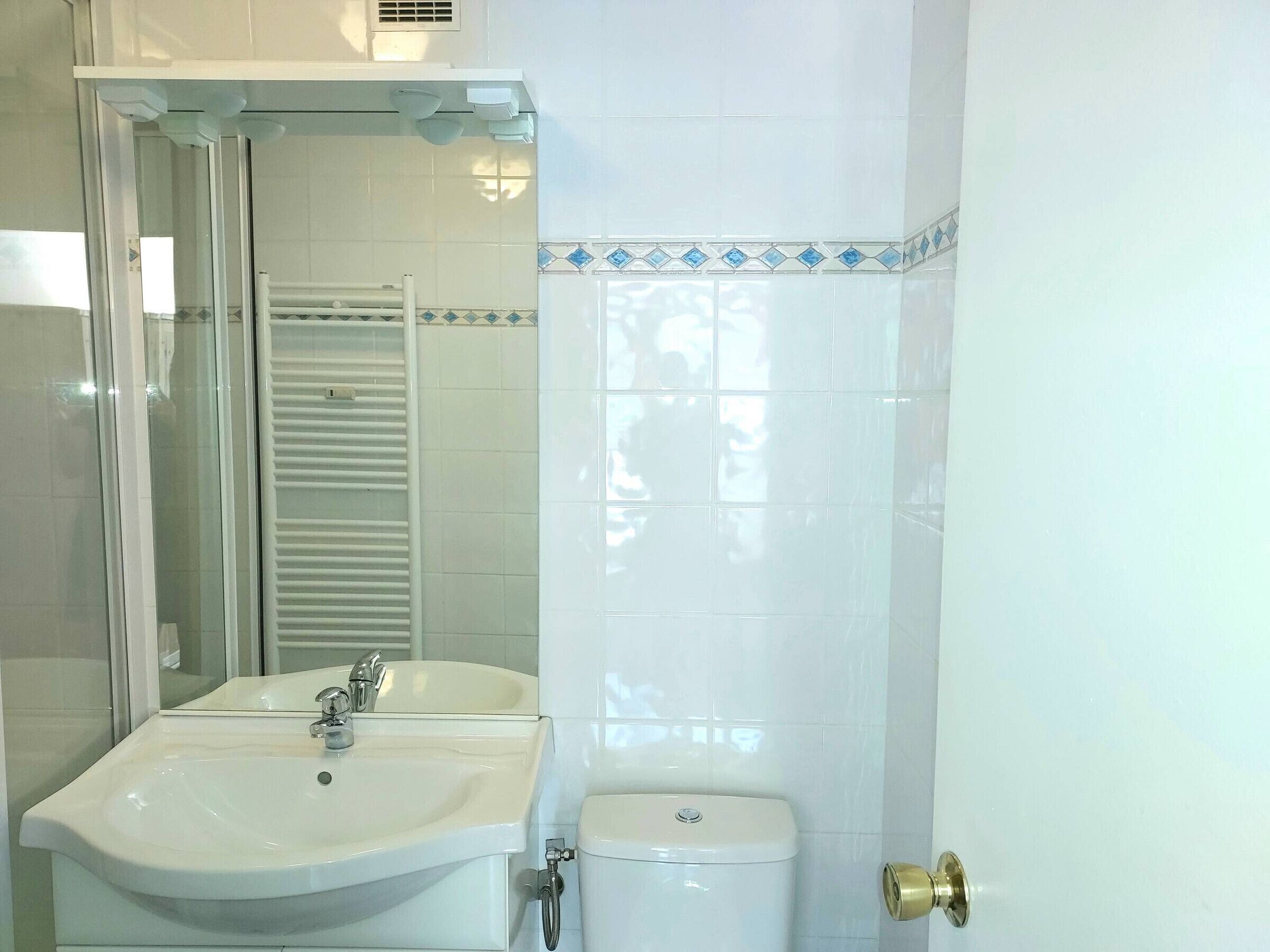 Un baño con lavamanos blanco, inodoro y cabina de ducha de vidrio.