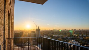 A balcony with a view of a cityscape during sunset. - Luxury two Bedroom Apartment (Barking)