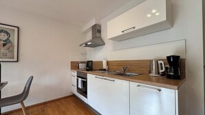A compact kitchen with white cabinets, a wooden countertop, a stainless steel sink, a coffee maker, and a toaster.