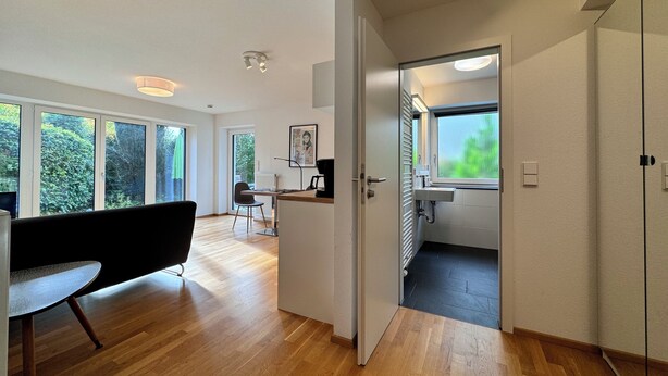 A modern interior with a dining area, kitchen, and a large window.