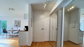 A modern interior with a wooden floor, a desk with a chair, a coffee machine, and a framed picture on the wall.